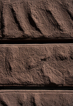 Rough textured brown stone or concrete architectural facade blocks