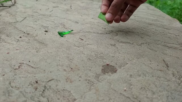 Person Picking Up Broken Green Glass Shards Outdoor Cleaning Concept