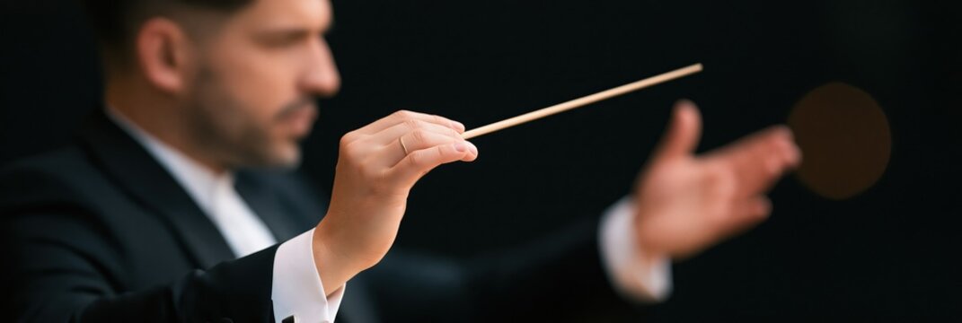 Focused image of conductor hands gripping baton and directing orchestra for concert promotion background banner and classical music event design