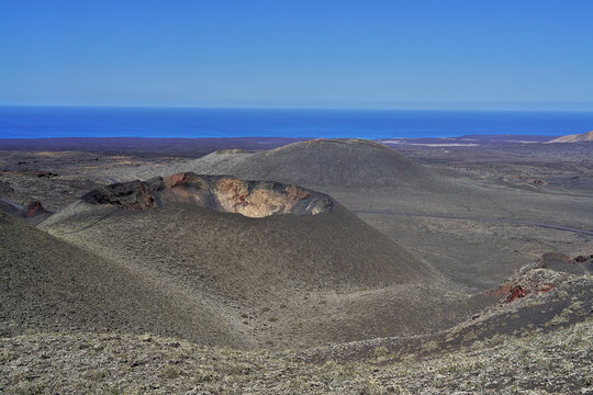 View of volcanic craters and arid landscape under a clear blue sky in Lanzarote, Canarias, Spain.