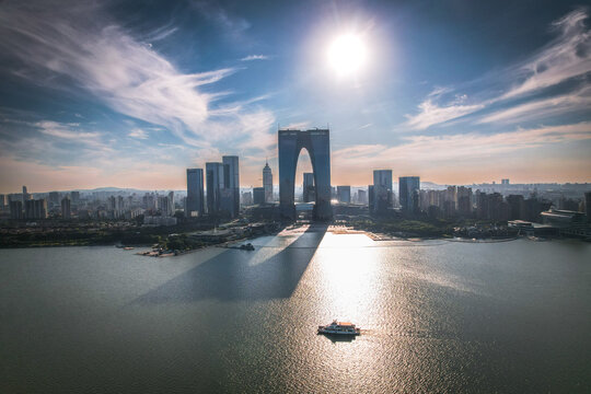 View of the Gate to the East skyscraper reflecting in the waters of Jinji Lake with a boat sailing across the modern skyline of Suzhou, Jiangsu, China.