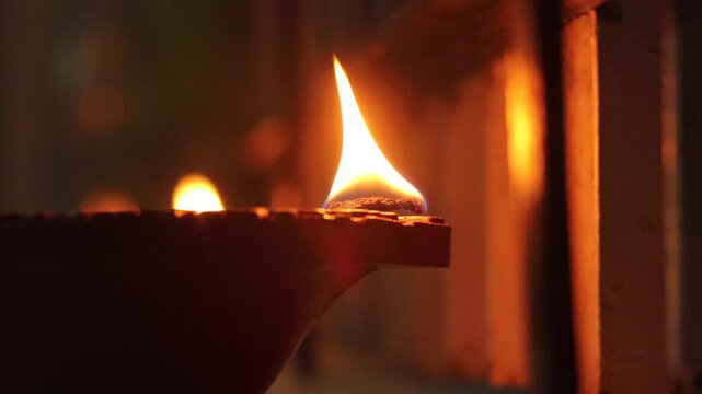 youtubTraditional Clay Diya Lamp Burning at Night Close Up, Warm Glowing Flame of Indian Oil Deepak for Happy Diwali Celebration, Hindu Puja Religious Festival, Spiritual Deepavali Background.e
