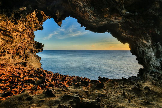 View of Ana Kakenga, the Cave of the Two Windows, with volcanic rock formations framing the vast Pacific Ocean at sunset, Easter Island, Valparaiso, Chile.