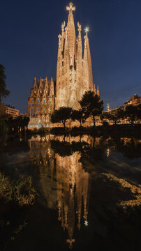 View of the illuminated Sagrada Familia reflecting in the calm water of a park pond at night in Barcelona, Catalonia, Spain.