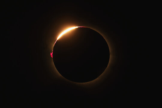 View of a total solar eclipse showing the diamond ring effect with a bright flare of sunlight emerging from behind the moon in Bellmunt del Priorat, Catalonia, Spain.
