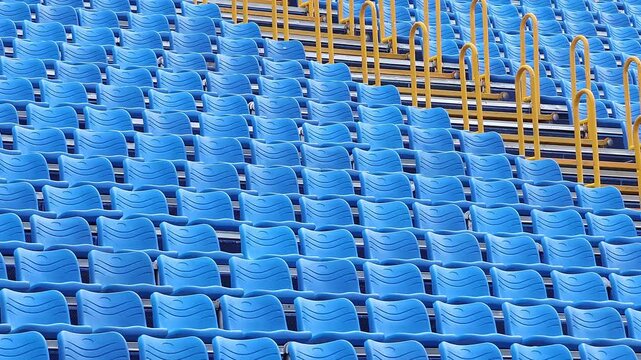 Empty Blue Chairs at Concert Arena. Rows of molded seats await visitors before a public performance. Concept of audience, entertainment, live shows, sports and event attendance.