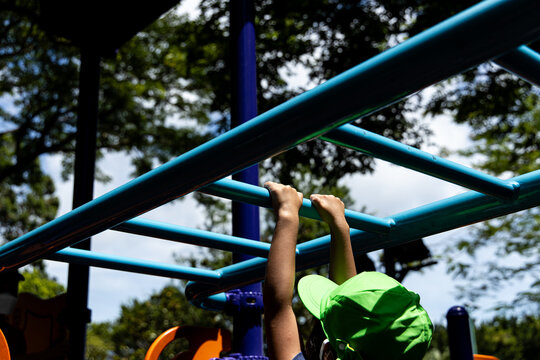 Child playing on monkey bars in a playground on a sunny day