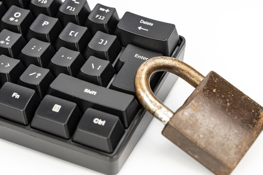 Close-up of a weathered rusty padlock resting against a black mechanical keyboard near the enter and delete keys, symbolizing cyber security, data protection, password safety, and online privacy risks