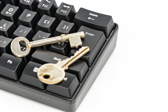 Close up of two vintage metal keys lying on a black computer keyboard next to Enter and Delete keys, symbolizing digital security, access control and password protection concept