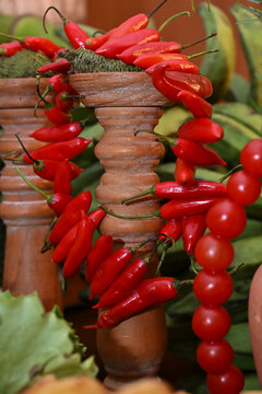 red pimenta dedo de mo&ccedil;a chili pepper garlands draped over terracotta pedestals with green bananas for brazilian feijoada buffet decoration, catering close up horizontal shot