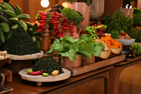 finely chopped couve collard greens, red pimenta dedo de mo&ccedil;a peppers, green lettuce, and rustic decorations on feijoada buffet table, catering display horizontal shot