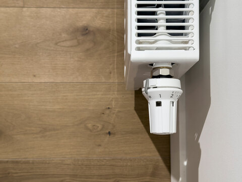 Thermostatic radiator valve on a wall mounted heater. Close up of heating control in a modern interior. Energy saving temperature regulation for home comfort..