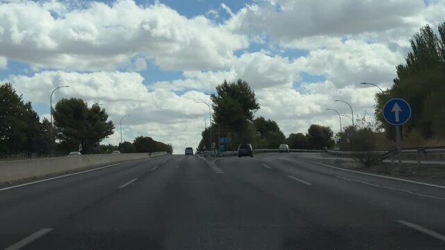 Scenic view from a car driving on a highway in Madrid, Spain. Road signs indicating directions to the airport and other locations