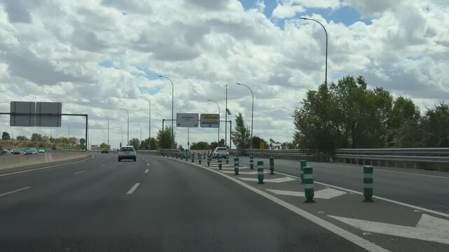 Driver's point of view driving on the M-11 highway in Madrid, Spain. Road signs indicating directions towards Valdebebas and Feria de Madrid