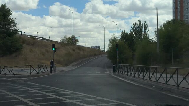 Point of view from a vehicle entering a highway ramp from a residential street. Traffic light turning green and car accelerating on the road