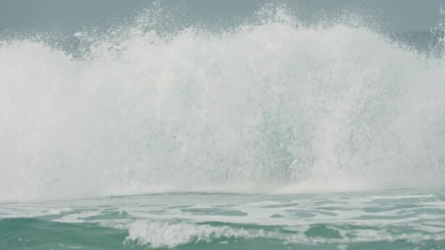 Huge turquoise wave creating a barrel and then crashing with immense force on a mexican shore