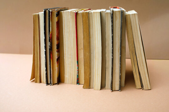 Stack of old books with worn covers standing on a beige background, perfect for back to school concept, high quality photo