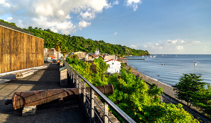 Obraz premium Scenic view of the coastline and town of Saint-Pierre in Martinique, featuring an old cannon at the historic fort ruins and the Caribbean sea.