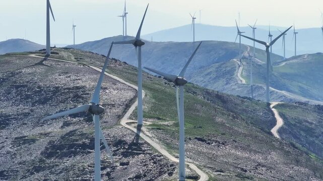 Numerous wind turbines spinning on a vast, hilly landscape, producing clean and sustainable electricity for a greener future