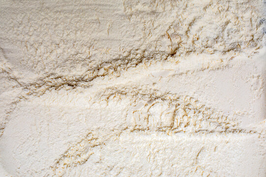 Close-up texture of white flour with delicate brown streaks forming a natural background pattern