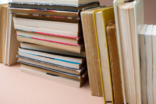 Stack of old books with worn covers standing on a beige background, perfect for back to school concept, high quality photo