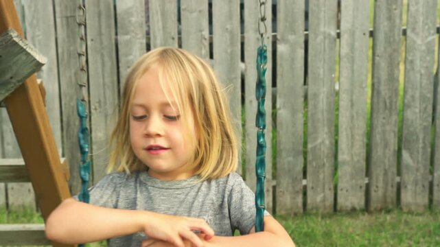 Smiling boy on a swing looking directly at the camera in a backyard setting
