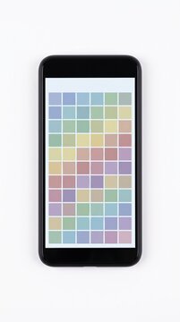 A smartphone screen shows a grid of soft pastel squares. This interface represents a calming mood tracker or meditation app layout. Ideal for concepts of digital wellness and mental health.