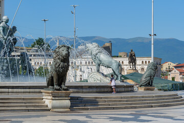 Skopje, North Macedonia – panoramic view of Macedonia Square with the monumental Warrior on a Horse statue, fountains, pedestrians and surrounding city architecture on a sunny summer day.  © Pawel 
