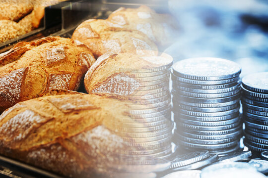 Fresh bread loaves combined with stacks of coins illustrate rising food costs and household expenses. Bakery products and money form an inflation and consumer price background.