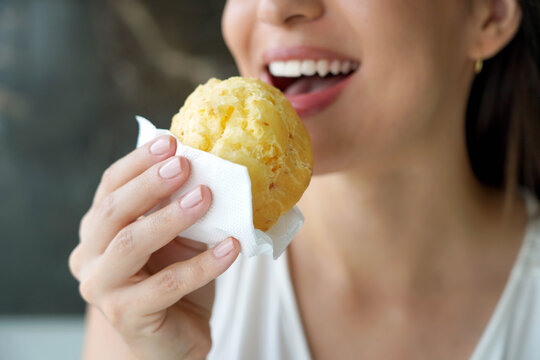 Pao de queijo (Brazilian cheese bun). Unidentified young woman eating pao de queijo Brazilian traditional recipe