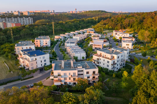 Suburban street scene captured during sunset. Neighbourhood full of newly built modern houses in quiet green area.