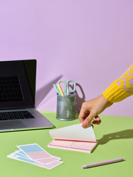 Woman's hand flipping through a notepad on a colorful desk