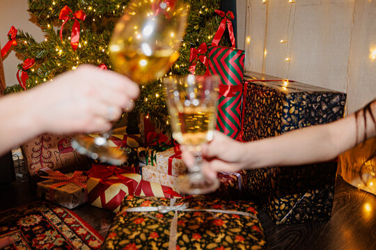 People Celebrate With Drinks Near a Christmas Tree and Gifts