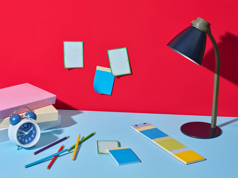 Colorful desk setup with alarm clock, lamp, and stationery