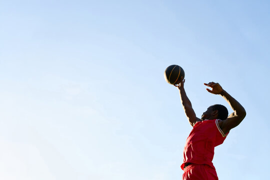Basketball Player Shoots Ball Against Clear Sky During Game