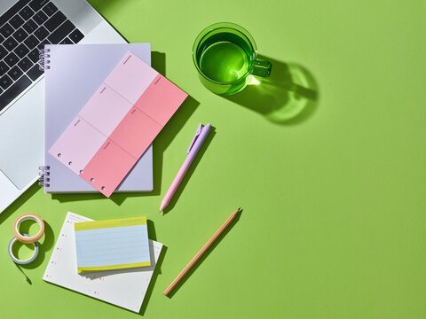 Workspace with planner, pen, pencil, and a glass of water on green