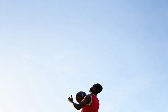 Young Player Practices Basketball Under Clear Sky