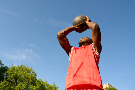 Player Shoots Basketball From Outdoor Court on Sunny Day