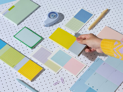 Colorful stationery and hand holding a notepad on a polka dot surface