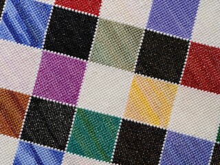 Fototapeta premium A close-up shot of a colorful checkered pattern hand-embroidered in cross-stitch.
