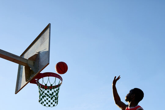 Basketball Player Shoots Ball Towards Hoop During Daytime Activity