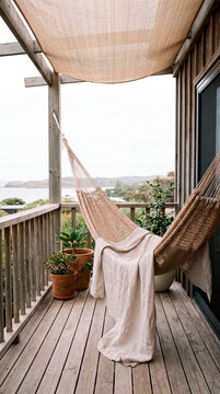Woven hammock drapes with linen throw on coastal deck overlooking distant sea