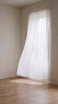 Sheer white curtain glows softly in empty minimalist room with wooden floor