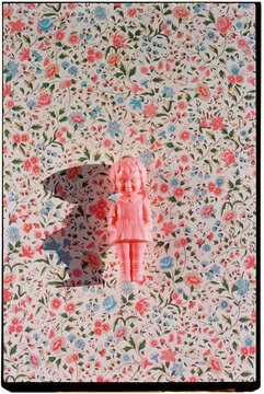 pink plastic doll beneath a wide floral pattern, 35mm film