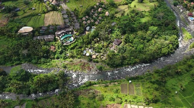 Aerial view of rocky stream winding through lush Mount Agung foothill rice terraces with flowing whitewater, with stream, river, water, flow detail, showing whitewater, rock, boulder, bank context