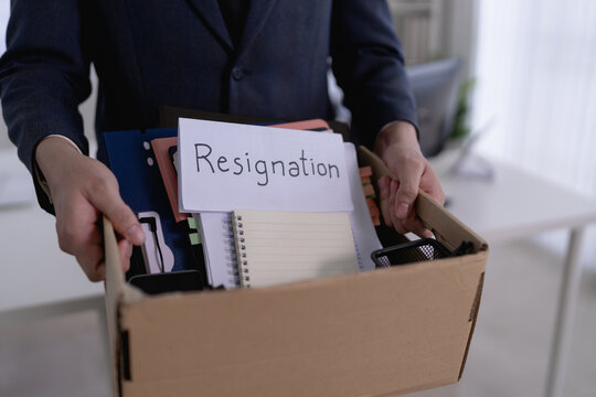 Asian businessman carrying resignation box with personal belongings leaving office after quitting job with copy space