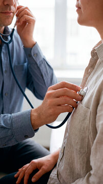 Doctor listens to patient heartbeat using stethoscope during checkup closeup