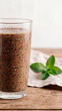 Chilled smoothie in glass garnished with fresh mint leaves on wooden table