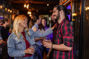 Fototapeta premium Blonde Woman and Young Man Chatting at Lively Pub