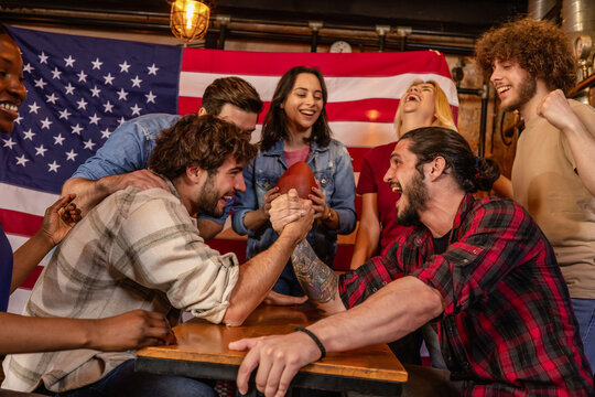 Friends Watching Exciting Arm Wrestling Showdown in Pub